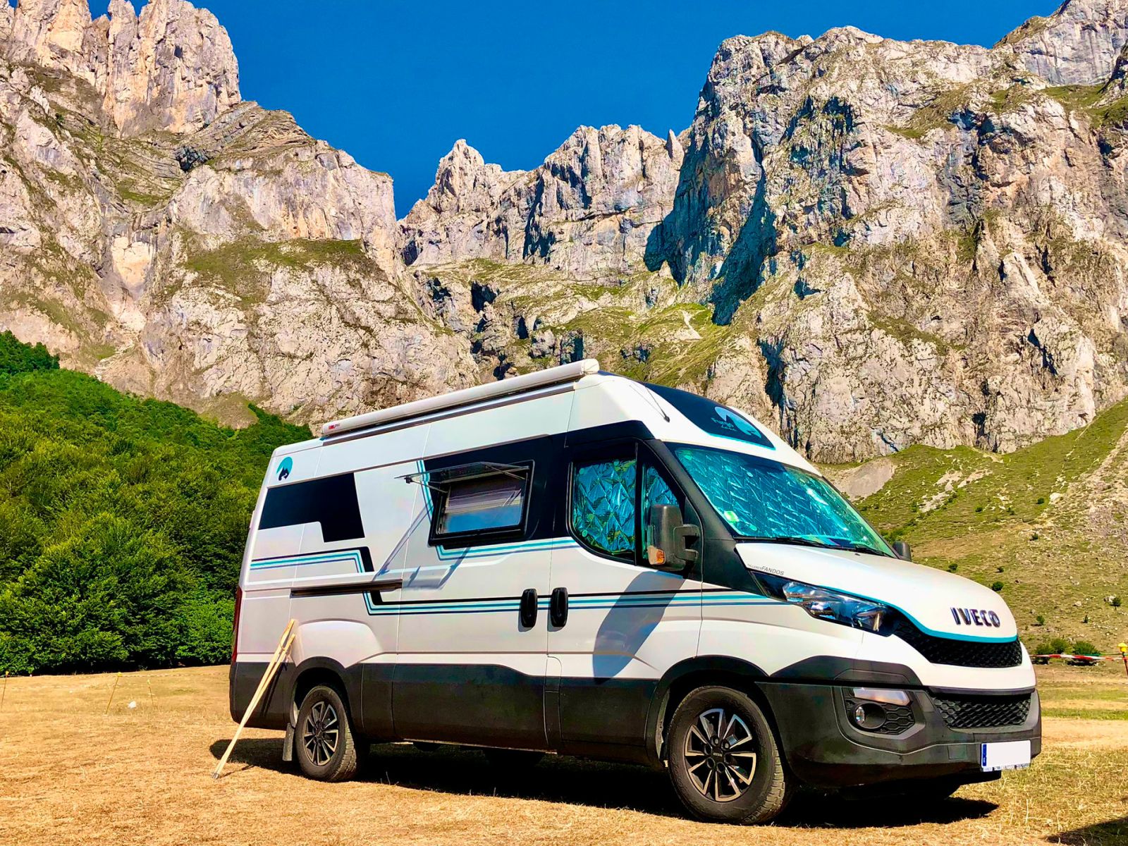 Imagen de furgoneta iveco camperizada de color blanco y azul entre montañas