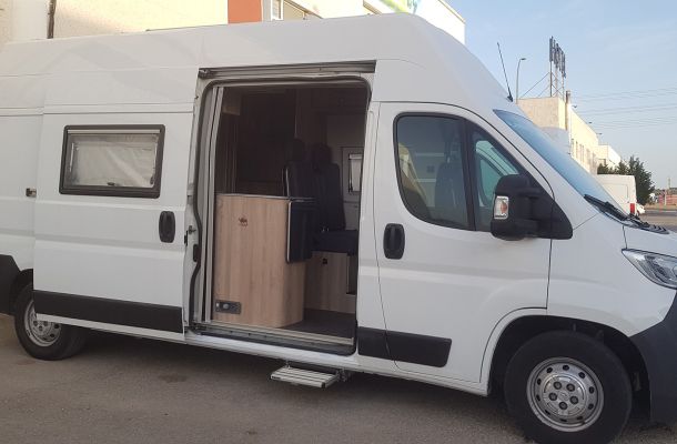 Furgoneta camperizada por dentro aparcada en el exterior del taller