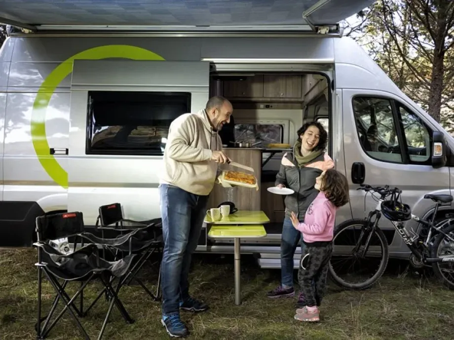 Imagen de furgoneta camperizada con familia en el exterior merendando