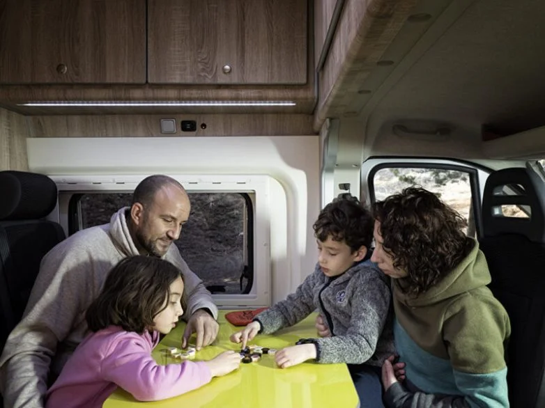 Imagen de una familia dentro de una autocaravana jugando con los niños 